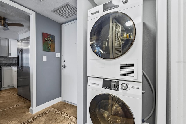 laundry room featuring light tile patterned floors and stacked washer / dryer