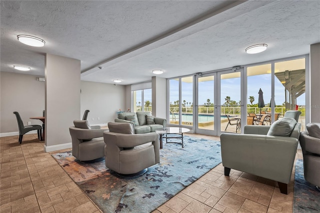 living room with a textured ceiling, a wall of windows, and a wealth of natural light