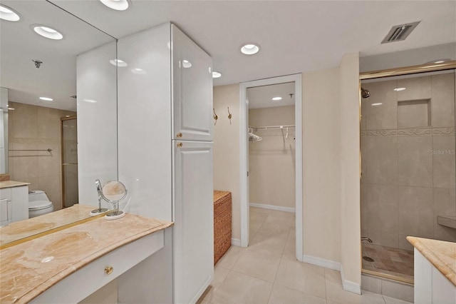 bathroom featuring walk in shower, vanity, tile patterned flooring, and toilet