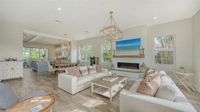 living room featuring beam ceiling, a large fireplace, and light hardwood / wood-style floors