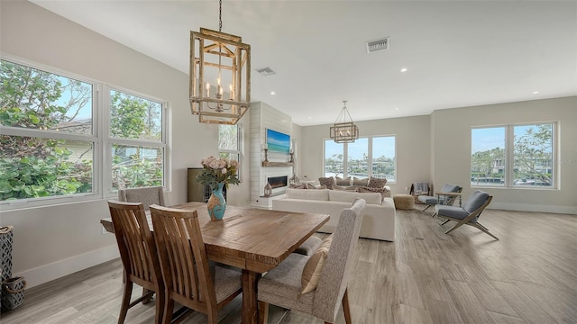 dining room with an inviting chandelier, light hardwood / wood-style floors, and a fireplace