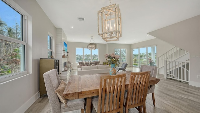 dining space with light hardwood / wood-style floors and a notable chandelier