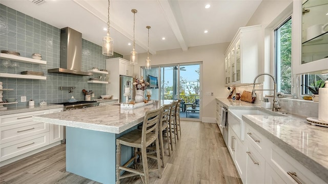 kitchen featuring white cabinetry and wall chimney range hood