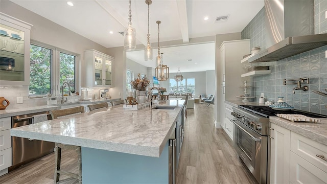 kitchen featuring white cabinetry, appliances with stainless steel finishes, and wall chimney exhaust hood