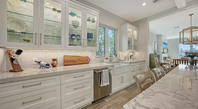 kitchen with pendant lighting, white cabinets, dishwasher, sink, and light hardwood / wood-style flooring