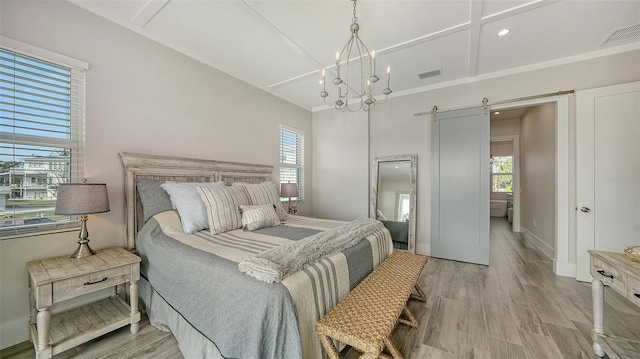 bedroom with a barn door, light wood-type flooring, a notable chandelier, and ornamental molding