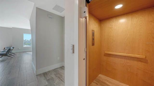 hall with hardwood / wood-style floors and elevator