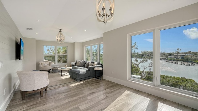 living room with an inviting chandelier, a wealth of natural light, and a water view