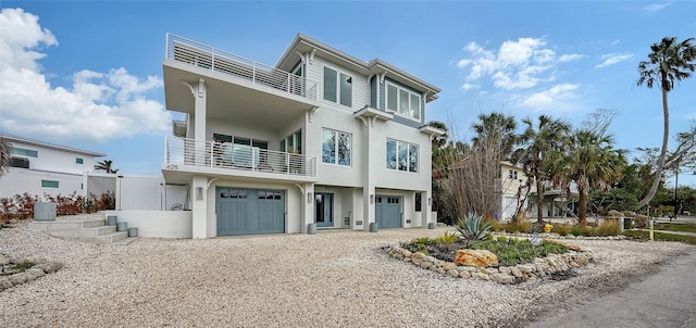 view of front facade with a garage, central AC, and a balcony