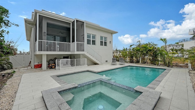 rear view of property featuring ceiling fan, a swimming pool with hot tub, a patio, and a sunroom