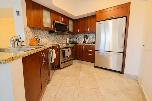 kitchen featuring light tile patterned floors, stainless steel appliances, decorative backsplash, light stone countertops, and sink