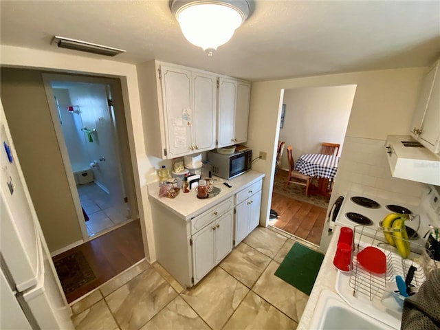 kitchen featuring white cabinets, light tile patterned flooring, and ventilation hood