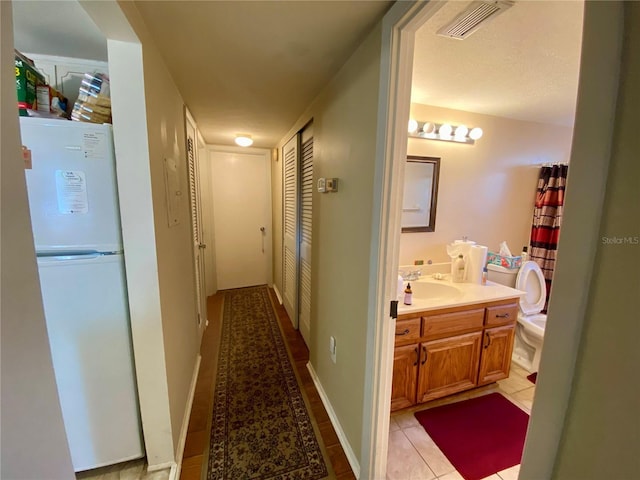 corridor featuring sink and light tile patterned floors