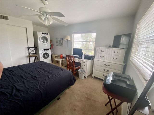 carpeted bedroom featuring stacked washer and dryer and ceiling fan