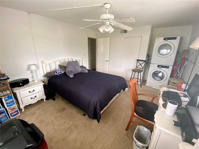 carpeted bedroom featuring ceiling fan and stacked washer / dryer