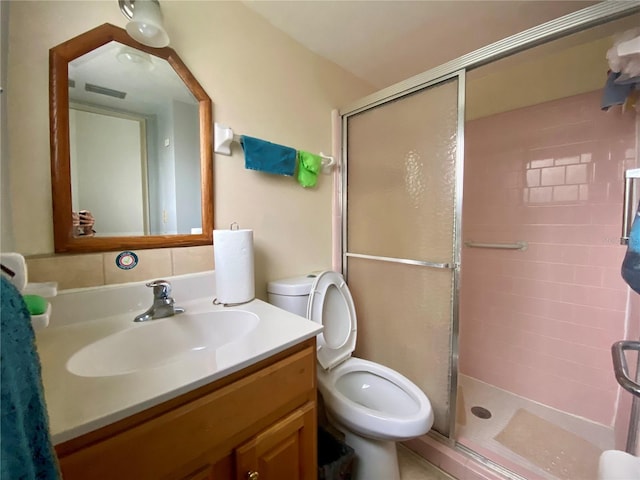 bathroom featuring toilet, a shower with door, and vanity