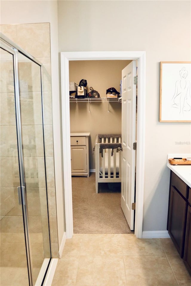 bathroom with a shower with shower door, vanity, and tile patterned floors