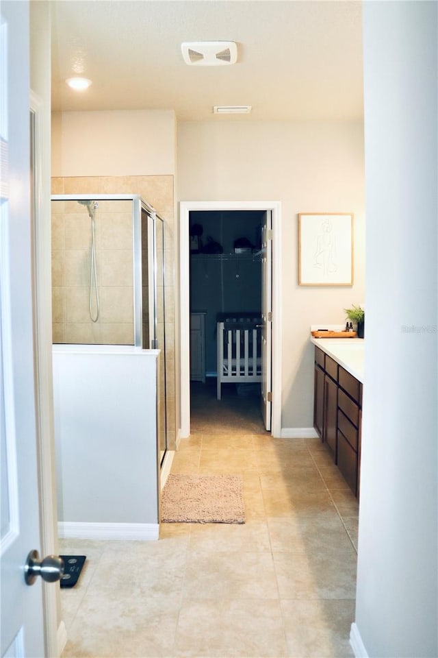 bathroom with an enclosed shower, vanity, and tile patterned flooring