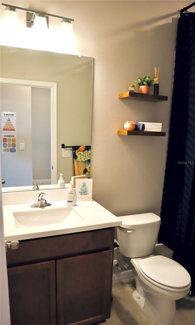 bathroom with toilet, vanity, and tile patterned flooring