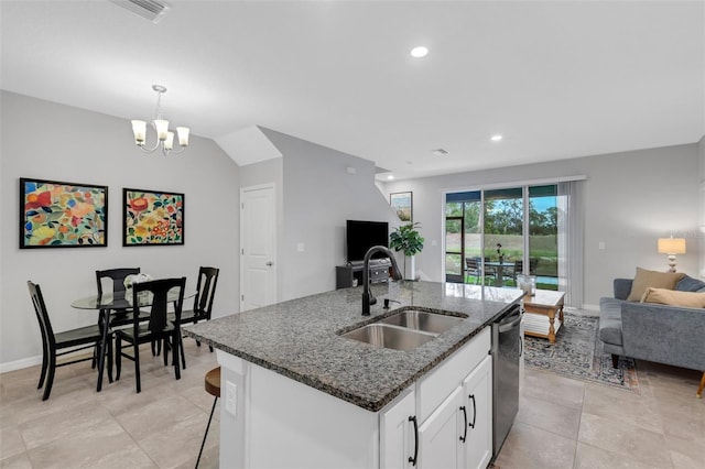 kitchen with stainless steel dishwasher, sink, white cabinetry, an island with sink, and dark stone counters