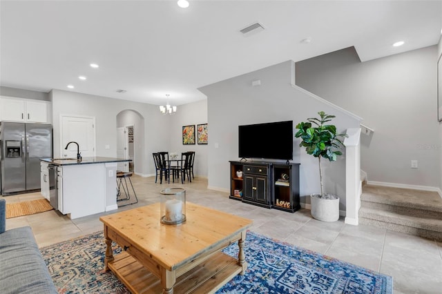 living room with an inviting chandelier, light tile patterned flooring, and sink