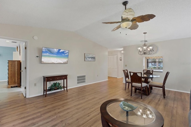 dining area with ceiling fan with notable chandelier, vaulted ceiling, and wood-type flooring