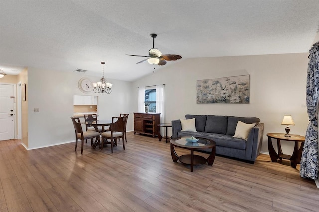 living room with a textured ceiling, vaulted ceiling, ceiling fan with notable chandelier, and hardwood / wood-style flooring