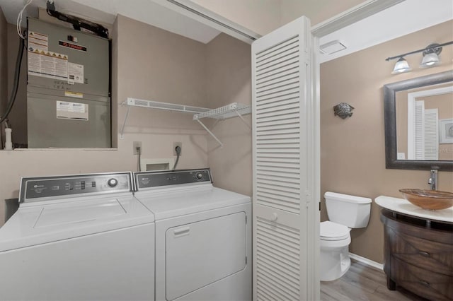 laundry area with sink, washer and dryer, and light wood-type flooring