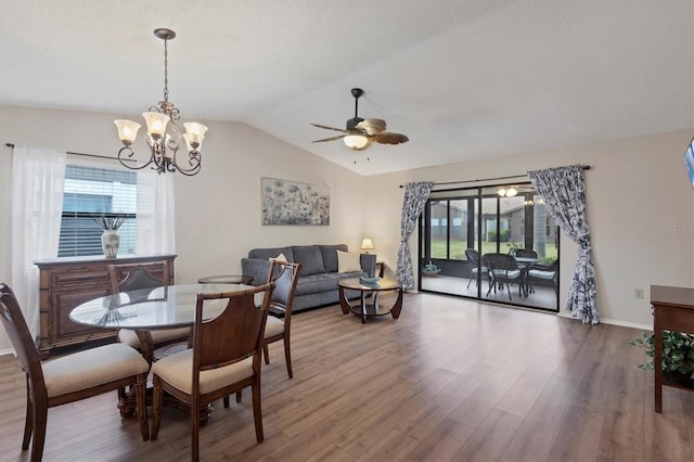 dining area featuring lofted ceiling, ceiling fan with notable chandelier, and hardwood / wood-style flooring