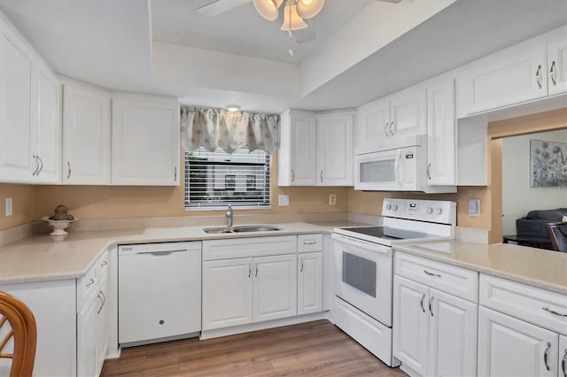 kitchen featuring white appliances, white cabinets, a tray ceiling, and sink