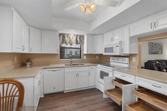 kitchen featuring white appliances, white cabinetry, sink, and a tray ceiling