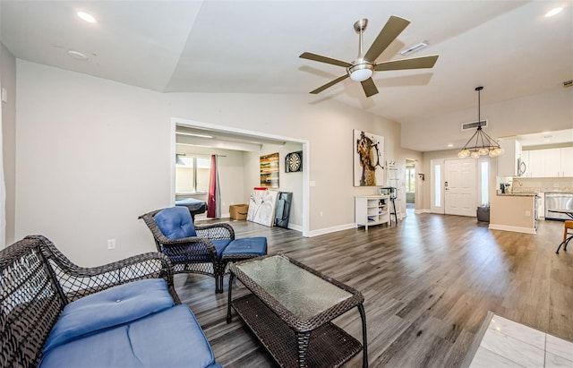 living room with ceiling fan with notable chandelier, sink, dark wood-type flooring, and vaulted ceiling