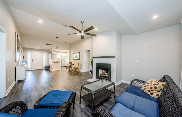 living room featuring ceiling fan, a fireplace, and dark hardwood / wood-style floors