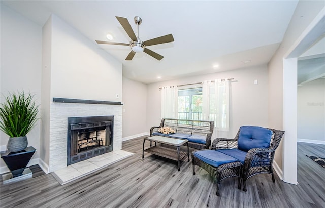 living room featuring a tile fireplace, hardwood / wood-style floors, ceiling fan, and lofted ceiling