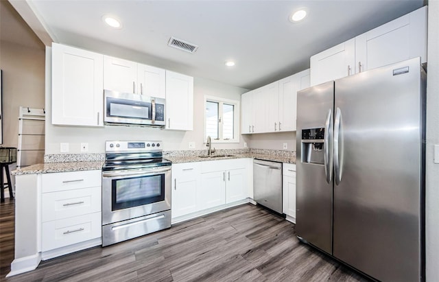 kitchen featuring white cabinets, sink, dark hardwood / wood-style floors, light stone countertops, and stainless steel appliances