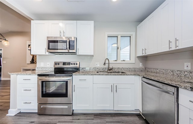 kitchen with light stone countertops, sink, white cabinets, and stainless steel appliances