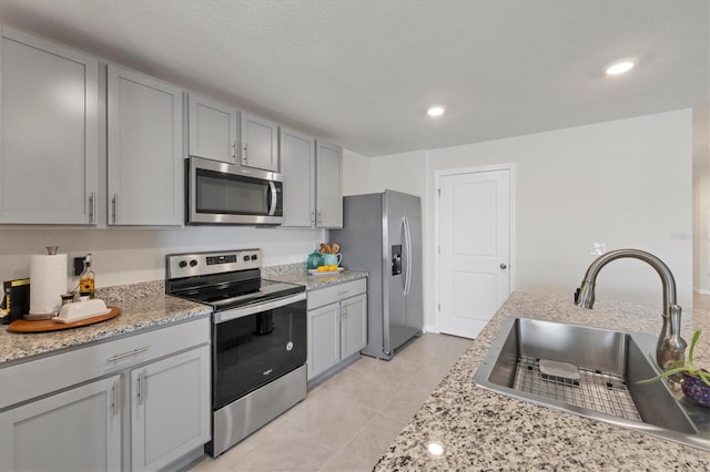 kitchen featuring appliances with stainless steel finishes, light tile patterned floors, gray cabinetry, and sink