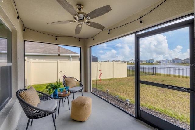 sunroom / solarium featuring ceiling fan and a water view