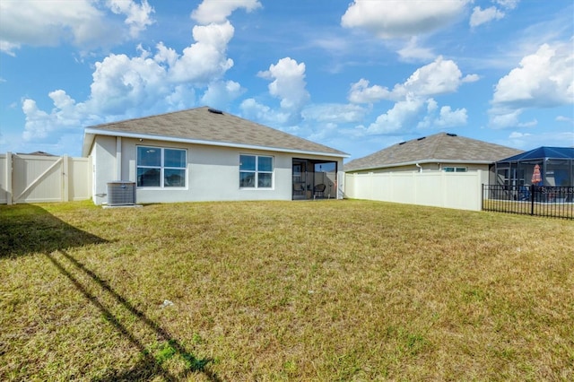 rear view of house featuring central AC unit and a lawn