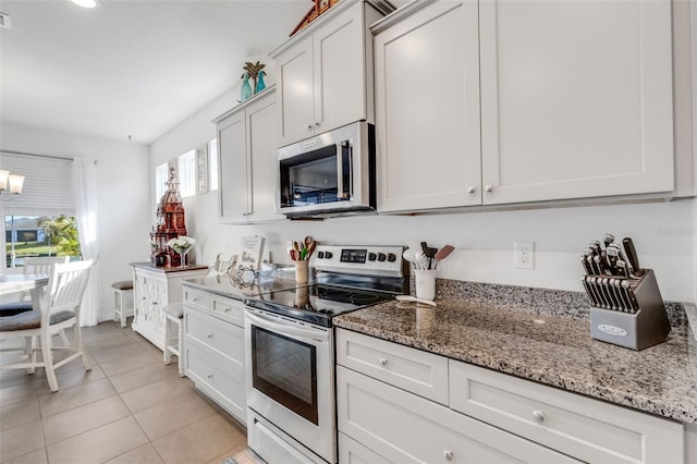 kitchen with light stone counters, stainless steel appliances, light tile patterned floors, and white cabinets