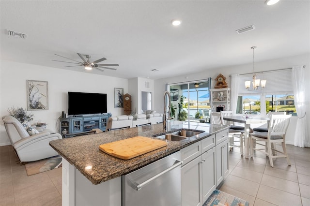 kitchen with dishwasher, a kitchen island with sink, dark stone counters, pendant lighting, and white cabinetry