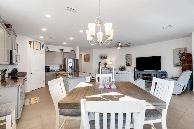 tiled dining room with ceiling fan with notable chandelier