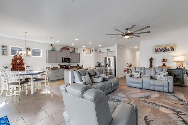 tiled living room with ceiling fan with notable chandelier