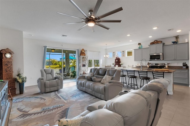 living room featuring ceiling fan with notable chandelier, light tile patterned flooring, and sink