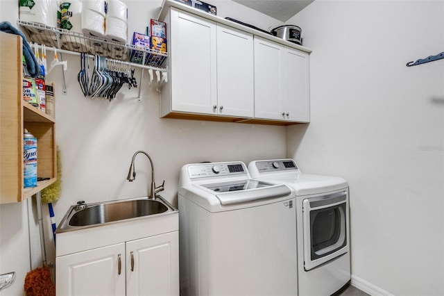 laundry area featuring sink, cabinets, and washer and clothes dryer