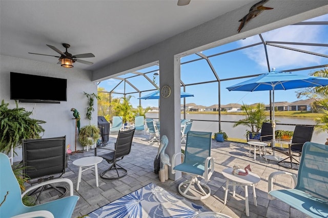 view of patio with ceiling fan, a water view, and glass enclosure