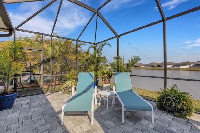 view of patio with a lanai and a water view