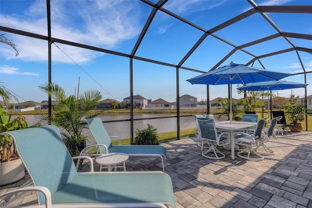 view of patio / terrace featuring a water view and glass enclosure