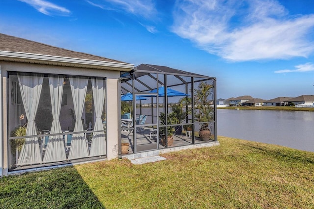 exterior space featuring a lanai, a water view, and a lawn