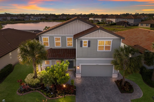 view of front of property featuring a water view, a yard, and a garage